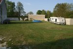 Vue du coté <br /><br />Piscine au fond, avec un bambou de planter, des buddléia à gauche, et un fuschia...<br /><br />Ou il y a la caravane, mon mari voulait installer un massif avec conifères, et fleurs, histoire de couper le terrain mais je suis pas convaincu...<br /><br />Nous pensions y installer aussi un saule.<br /><br />Adossé au mur de la maison, ce sera un abri pour le bois, je voudrai y faire courir un glycine (mais apparemment ici c'est trop calcaire, et la nappe est pas loin, donc le voisin m'a dit que chez lui elle a jamais prise)<br /><br />Vous le voyez pas sur la photo mais une barrière en bois à été mise à gauche qui va de la maison jusqu'au mur, étant ass mat j'ai créer un espace jeu sécurisée.